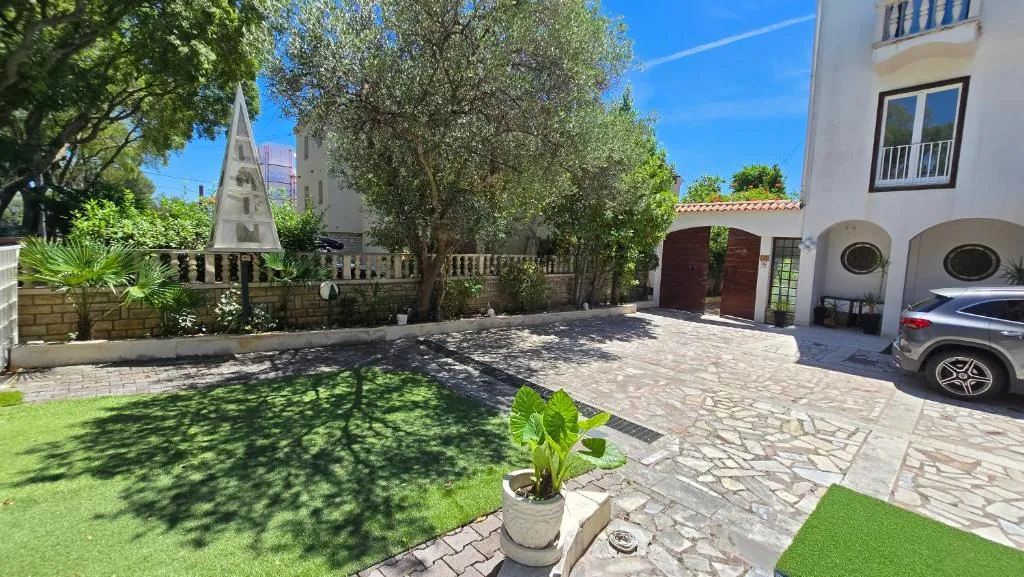 Paved courtyard with lawn and on-site parking in front of the house