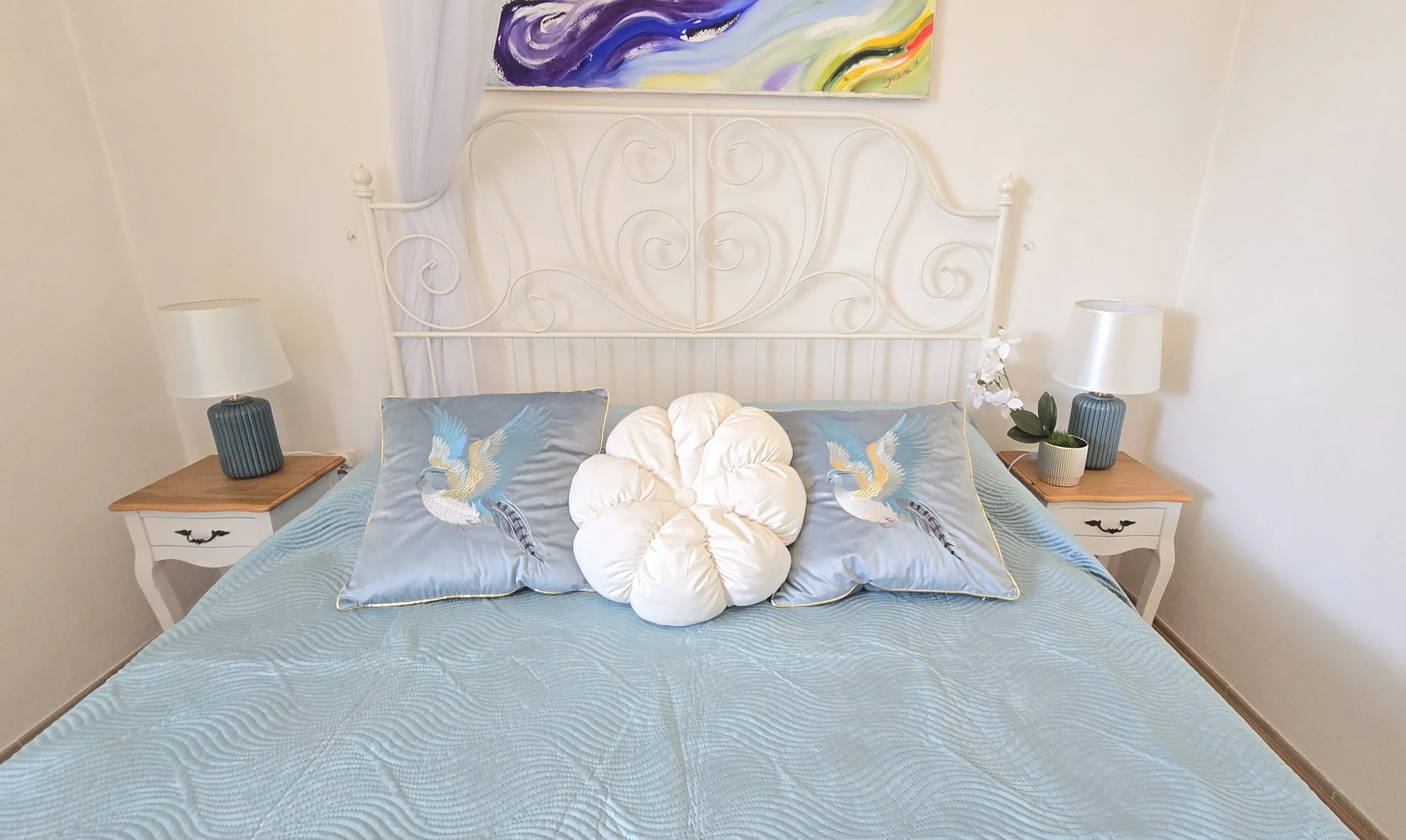 Apartment bedroom with a white wrought-iron bed