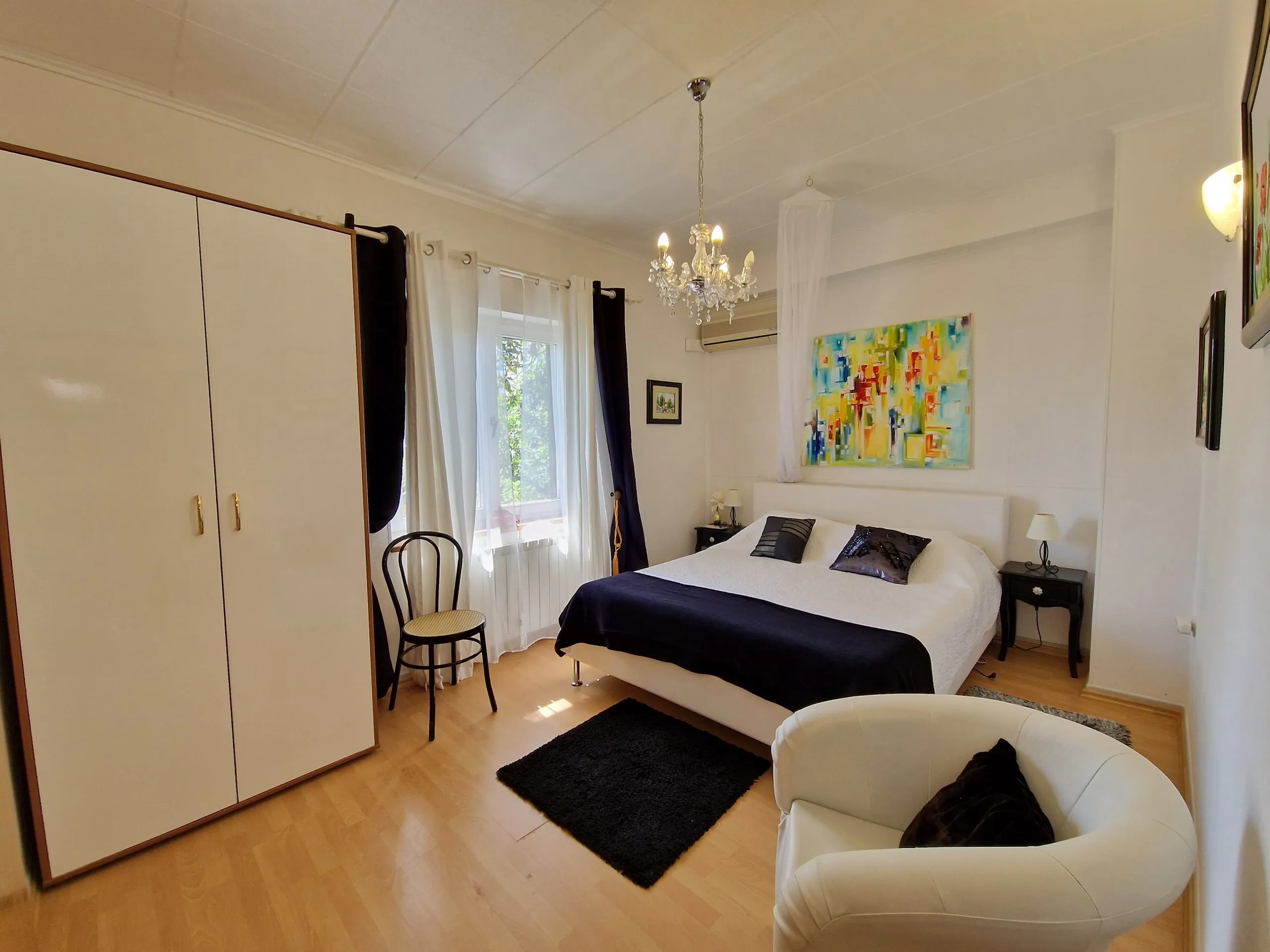Quadruple room with a chandelier, armchair and original paintings