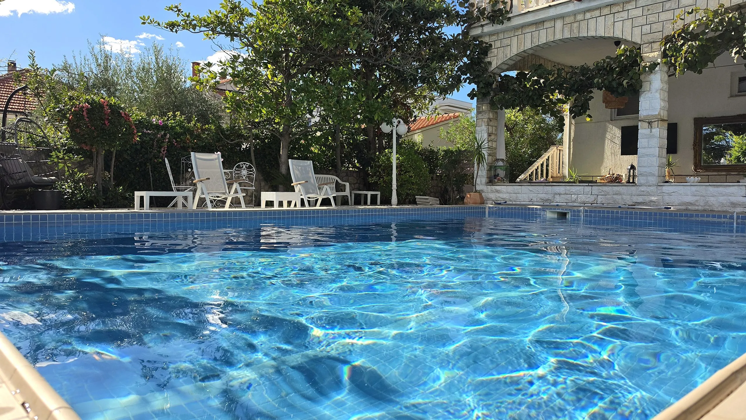 Pool with sun loungers shaded by olive trees and greenery