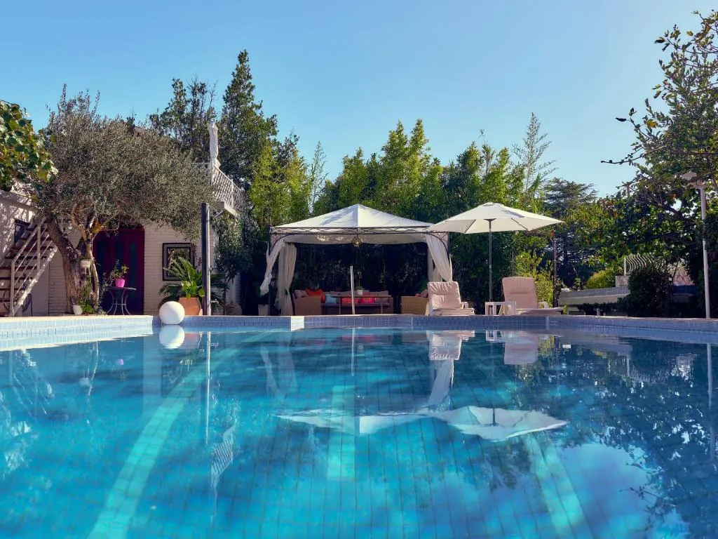 Pool reflecting the gazebos, parasols and olive trees